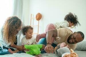 Happy African American Parents with  little daughters playing on the bed in bedroom at home, happy family concept photo