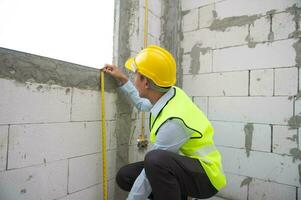 An Asian Engineering man wearing safety helmet checking construction site analyzing about project progress photo