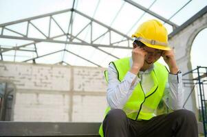 An Asian Engineering man with safety helmet feeling sad in construction site photo
