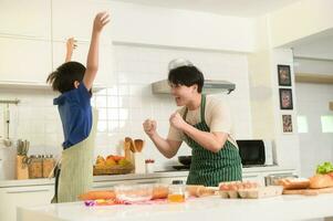 contento joven asiático padre y hijo Cocinando en cocina a hogar foto