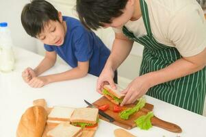 Happy Young Asian father and son eating healthy food in kitchen at home photo