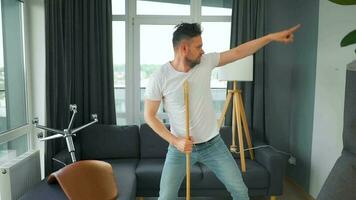 Man cleaning the house, having fun dancing and singing with a broom. video