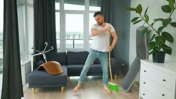 homem limpeza a casa e tendo Diversão dançando com uma vassoura. lento movimento video
