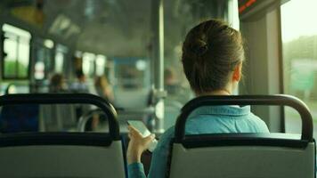 Woman in tram using smartphone chatting and texting with friends, back view video