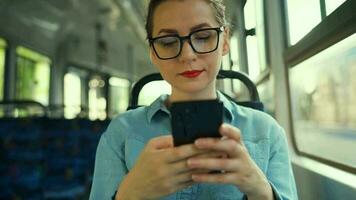 vrouw in tram gebruik makend van smartphone chatten en sms'en met vrienden. stad, stedelijk, vervoer. langzaam beweging video