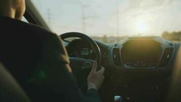 Mens schijven een auto langs de weg, de instelling zon schijnt in de voorruit video