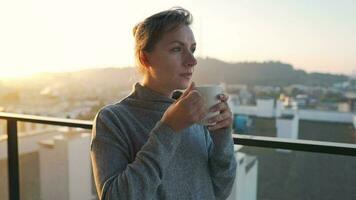 mujer empieza su día con un taza de té o café en el balcón a amanecer video