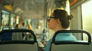 femme dans tram en utilisant téléphone intelligent bavardage et envoyer des SMS avec amis, retour vue video