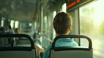 Woman in tram using smartphone chatting and texting with friends, back view video