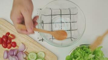 cuisine - femme fabrication Frais biologique légume salade dans le cuisine. femelle mains en train de préparer délicieux en bonne santé nourriture à maison, mélange des légumes dans une bol, fermer. video