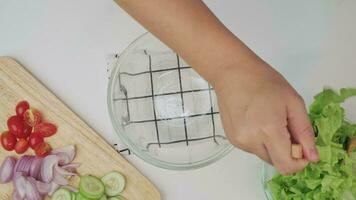 cuisine - femme fabrication Frais biologique légume salade dans le cuisine. femelle mains en train de préparer délicieux en bonne santé nourriture à maison, mélange des légumes dans une bol, fermer. video