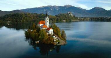 aéreo Visão do lago sangrar e a ilha dentro a meio do isto, eslovênia. peregrinação Igreja do a suposição do Maria dentro lago sangrar video