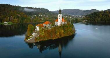 aéreo Visão do lago sangrar e a ilha dentro a meio do isto, eslovênia. peregrinação Igreja do a suposição do Maria dentro lago sangrar video