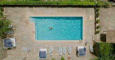 View from the top as a woman in red swimsuit swims in the pool video