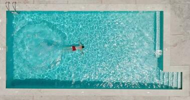 Visualizza a partire dal il superiore come un' donna nel rosso costume da bagno nuotate nel il piscina video