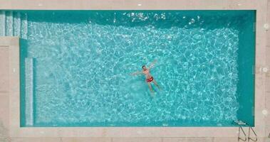 ver desde el parte superior como un mujer en rojo traje de baño nada en el piscina video