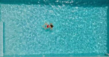 Aussicht von das oben wie ein Frau im rot Badeanzug schwimmt im das Schwimmbad video