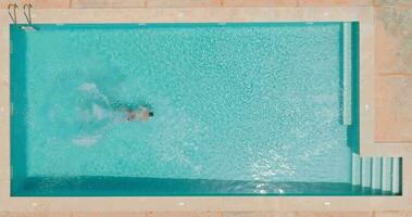 ver desde el parte superior como un mujer en rojo traje de baño nada en el piscina video