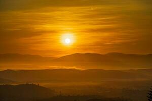 Mountain range with visible silhouettes through the morning colorful fog photo