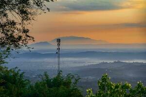 Mountain range with visible silhouettes through the morning colorful fog photo