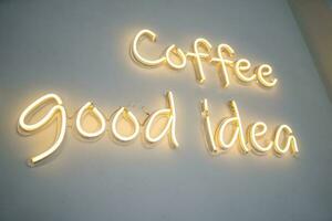 A yellow neon sign on white wall at coffee shop. photo