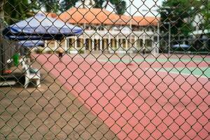 metal malla en un borroso antecedentes de un tenis Corte con jugadores foto