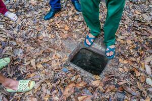 The Cu Chi tunnels. A guide demonstrating how a Vietcong hide into the Tunnel. It's used in Vietnam war. Famous tourist attraction in Vietnam. Stock photo