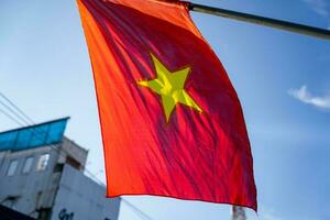 Vietnamese flag waving in the wind on a pole against a blue sky background photo