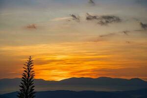 Mountain range with visible silhouettes through the morning colorful fog photo