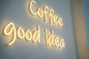 A yellow neon sign on white wall at coffee shop. photo
