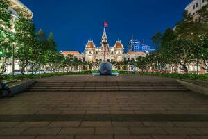 Ho Chi Minh, Viet Nam - 10 April 2023 Saigon City Hall, Vincom Center towers, colorful street traffic and tropical plants against the amazing night. Saigon downtown with its famous landmarks. photo