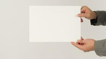 Two hands holding blank board white paper and wearing a grey suit on white background.  Space for text. photo
