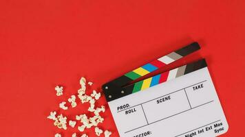 Clapper board or movie slate and popcorn on a red background. photo