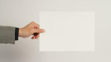 The male hand is holding the A4 paper board on white background. photo