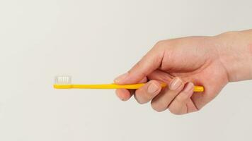 Hand holding yellow toothbrush on white background. photo