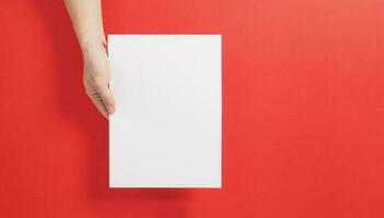 un mano es participación el blanco a4 papel en rojo antecedentes. foto