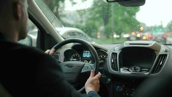 homem drives uma carro ao longo a estrada dentro a cidade durante a chuva video