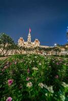 Ho Chi Minh, Viet Nam - 10 April 2023 Saigon City Hall, Vincom Center towers, colorful street traffic and tropical plants against the amazing night. Saigon downtown with its famous landmarks. photo