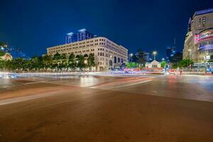 Ho Chi Minh, Viet Nam - 10 April 2023 Saigon City Hall, Vincom Center towers, colorful street traffic and tropical plants against the amazing night. Saigon downtown with its famous landmarks. photo