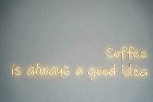 A yellow neon sign on white wall at coffee shop. photo