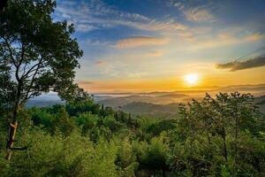 Mountain range with visible silhouettes through the morning colorful fog photo