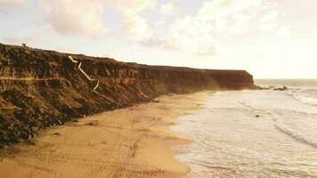 fliegend Über ein sandig Strand beim Sonnenuntergang, hoch Ufer. video