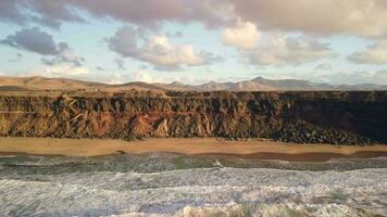 hoog rotsachtig kusten van de kanarie eilanden, de camera vliegt langs de strand. video
