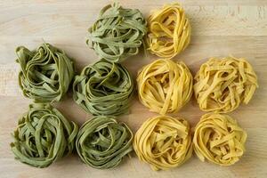 tagliatelle de pasta fresca casera verde y amarilla. pasta cruda casera de espinacas. foto