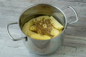 Raw peeled potatoes in a pot of water before cooking photo