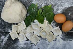 dough with spinach eggs, flour and ravioli on wood photo