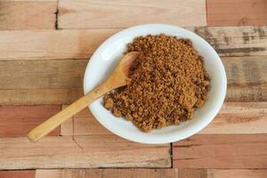 bowl with unrefined brown sugar on wooden background photo