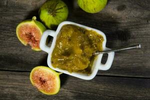 Homemade sweet of green figs. fig jam on rustic wooden background photo