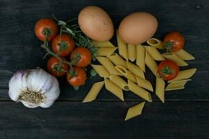kitchen background with noodles, eggs, cherry tomatoes, and garlic photo
