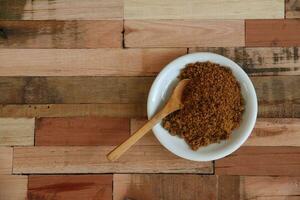 bowl with unrefined brown sugar on wooden background photo